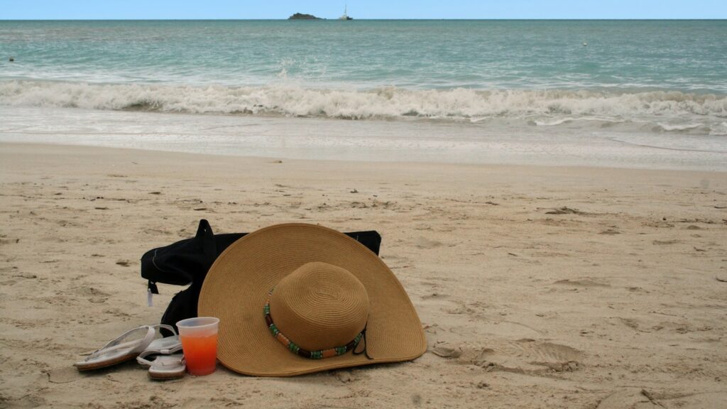 A sun hat and sunglasses on a sandy beach