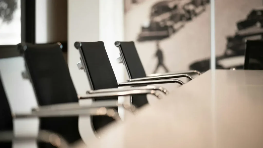 Row of black office chairs along an empty white meeting table