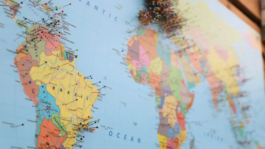 A printed world map on a wall marked with many small pins
