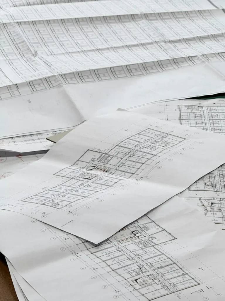 Stacked architectural blueprints on a desk